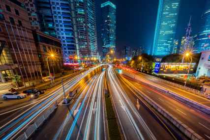 timelapse photography of vehicle on concrete road near in high rise building during nighttime